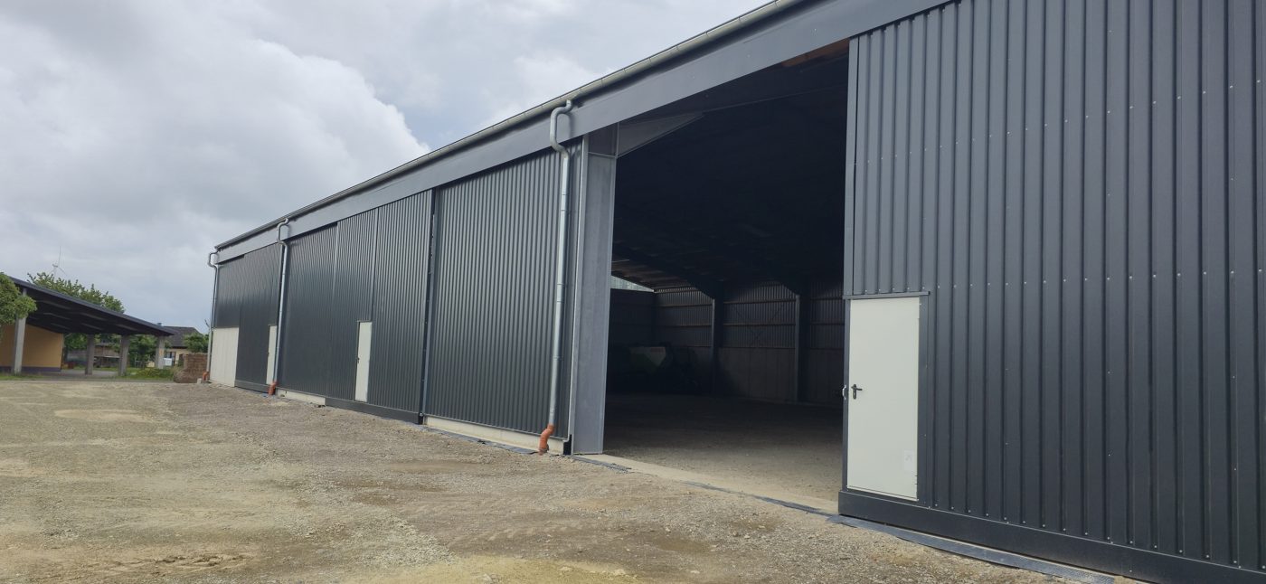 Schiebetore an einer 50 × 25 m Gerätehalle in der Vulkaneifel: breit genug für Mähdrescher und Ladewagen.